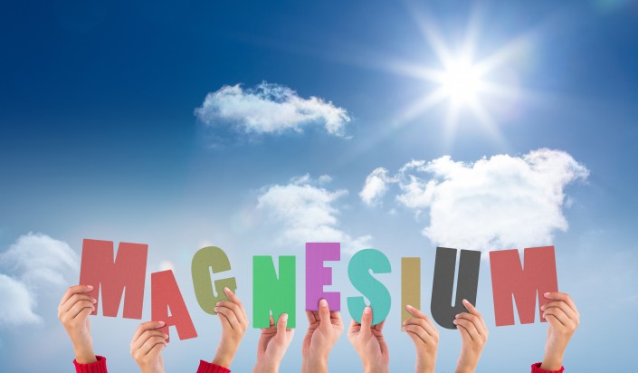 Hands holding up magnesium against bright blue sky with clouds