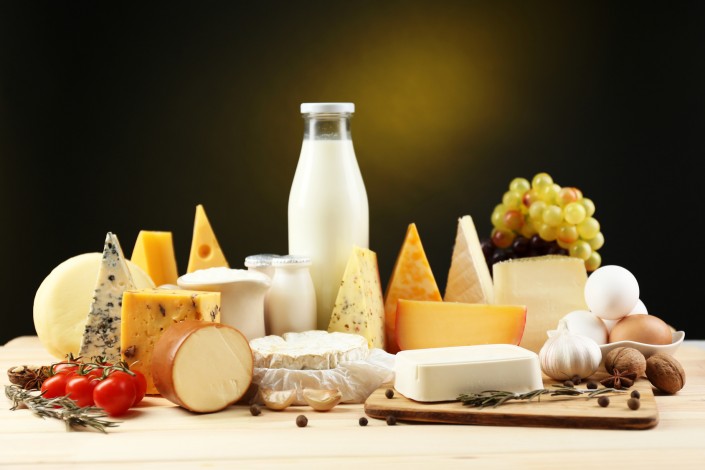 Tasty dairy products on wooden table, on dark background