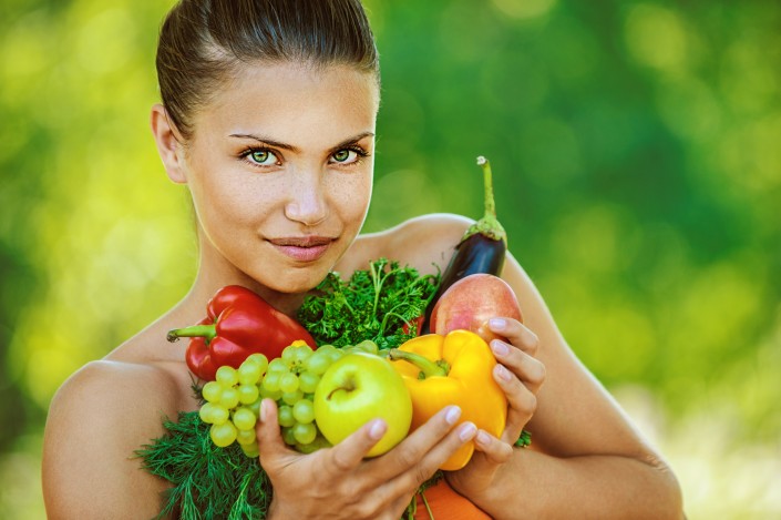 woman with bare shoulders holding fruit and vegetables
