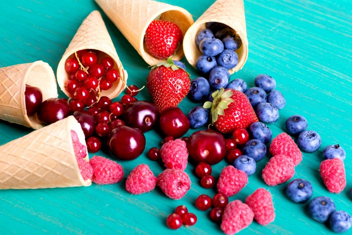 Berries poured out from cones on a gray table.