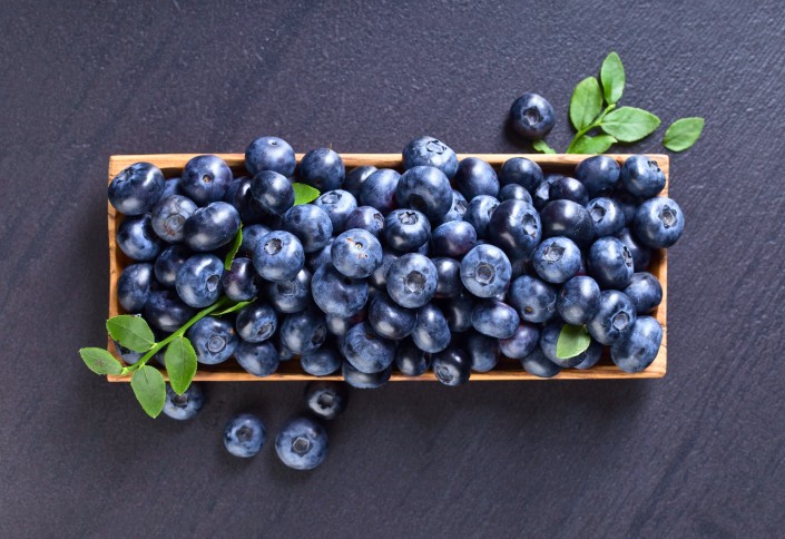 Blueberries in old wooden dish .
