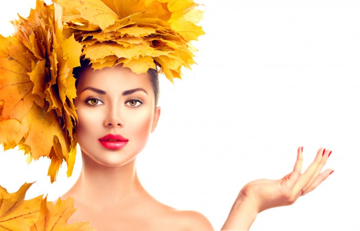 Fall. Beauty model girl with autumn bright leaves hairstyle. Girl showing empty copy space on open hand palm