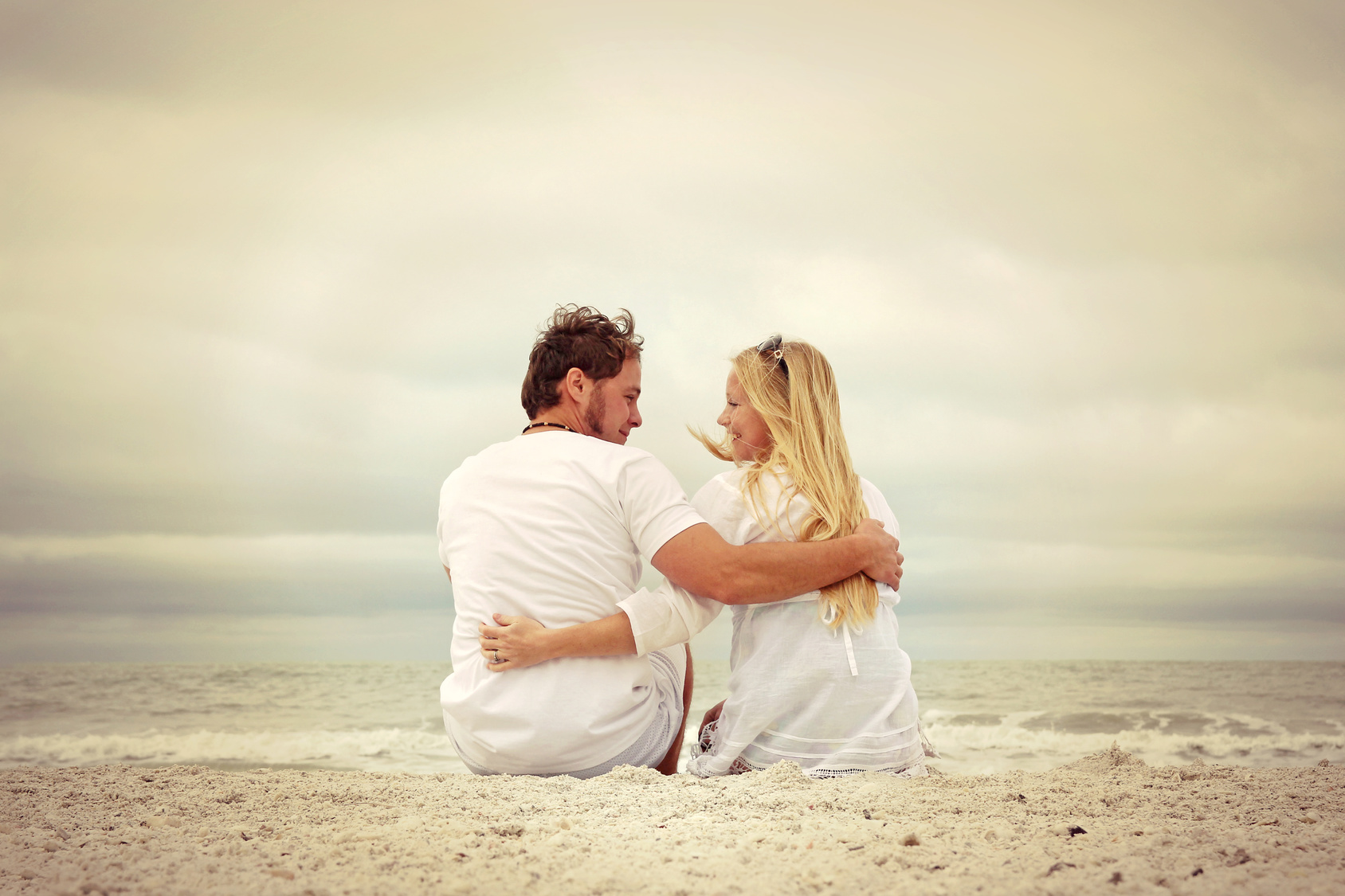 Happy Couple Sitting on Beach by Ocean in Vintage Color