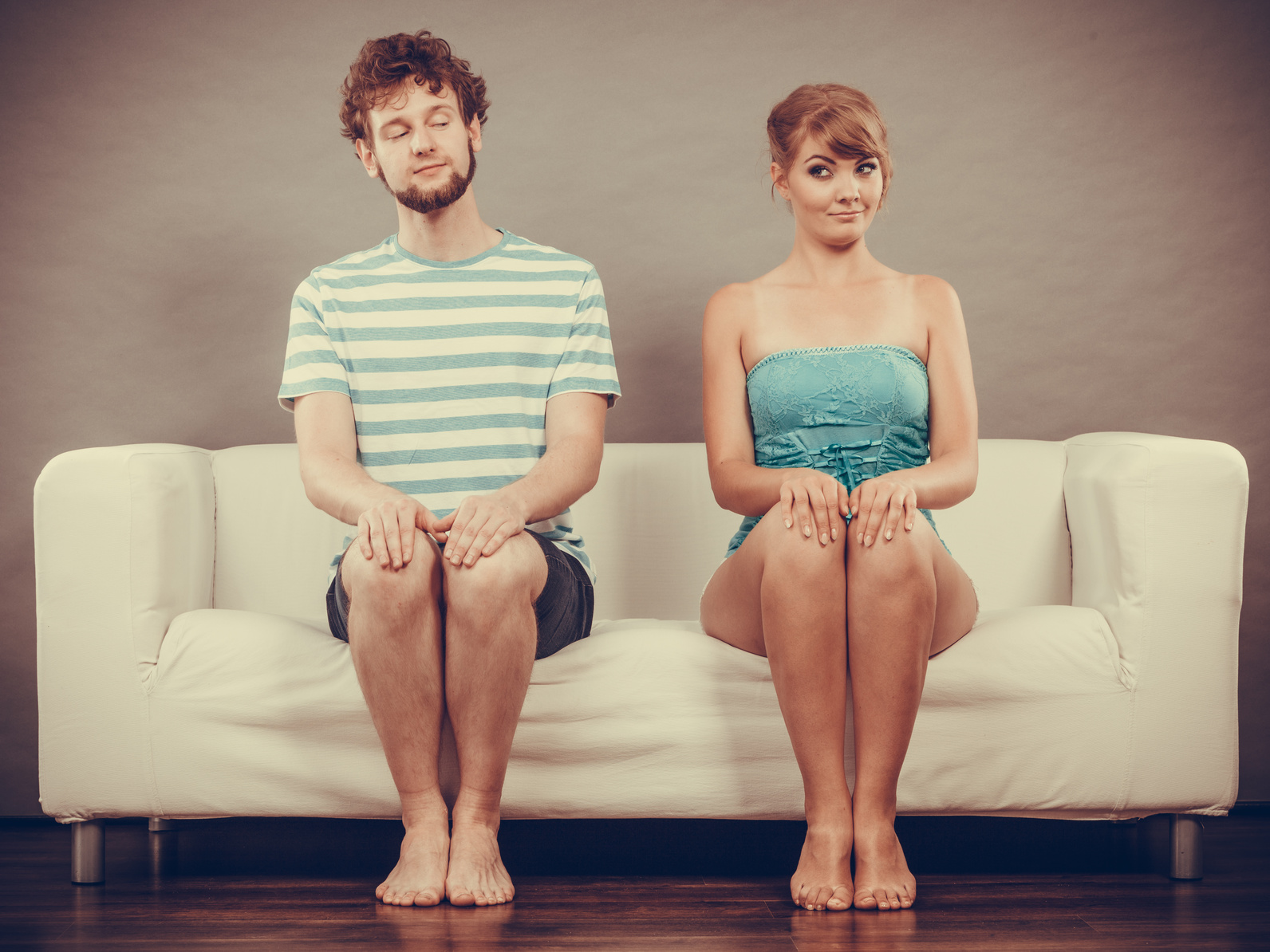 Shy woman and man sitting close to each other on couch.