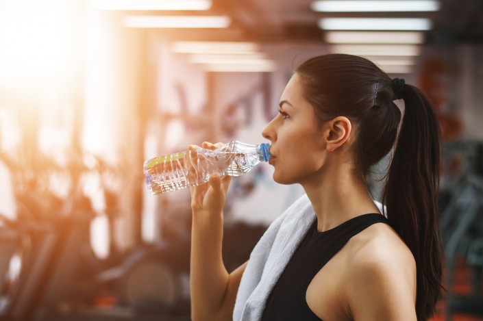Refreshing after workout. Beautiful young woman in sports clothi