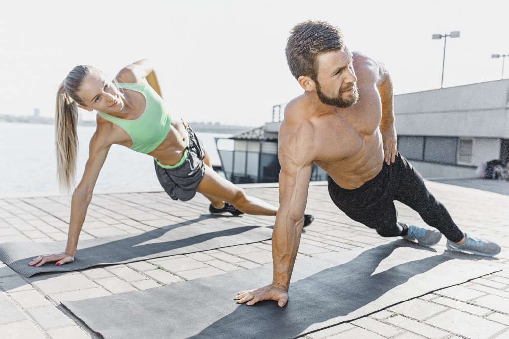 Fit fitness woman and man doing fitness exercises outdoors at city