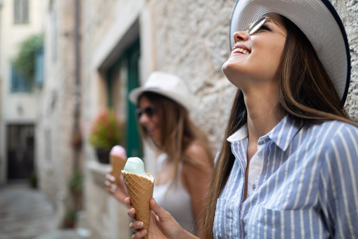 Two young female friends having fun and eating ice cream.