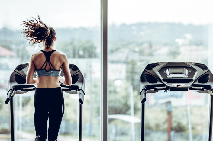 Attractive woman running on treadmill in sport gym