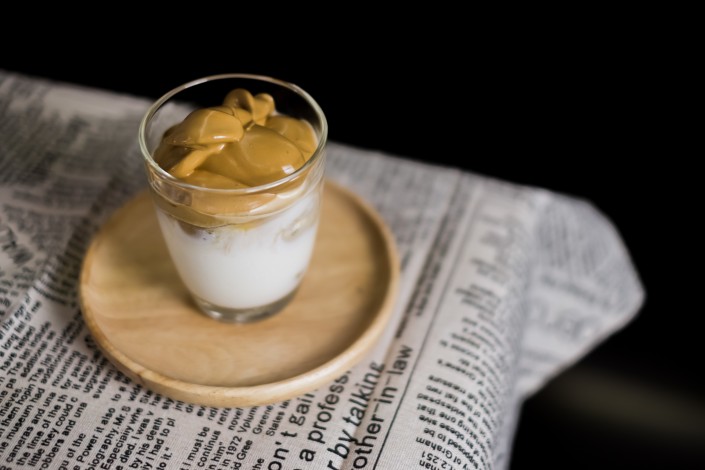 Iced Dalgona Coffee, a trendy korean style cremy whipped coffee on fresh milk, on wooden tray on the table