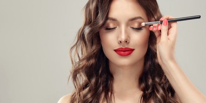 Makeup artist applies eye shadow . Beautiful woman face. Hand of visagiste, painting cosmetics of young beauty model girl . Make up in process
