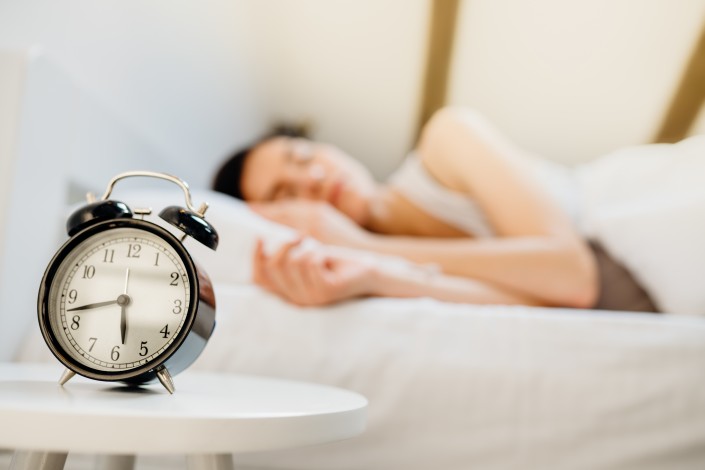 Alarm clock ringing.Woman waking up in early morning for work.Obstructive sleep apnea effects.Mental stress sleep depression.Melatonin deficiency.Narcolepsy.Burn out syndrome,overworked parent