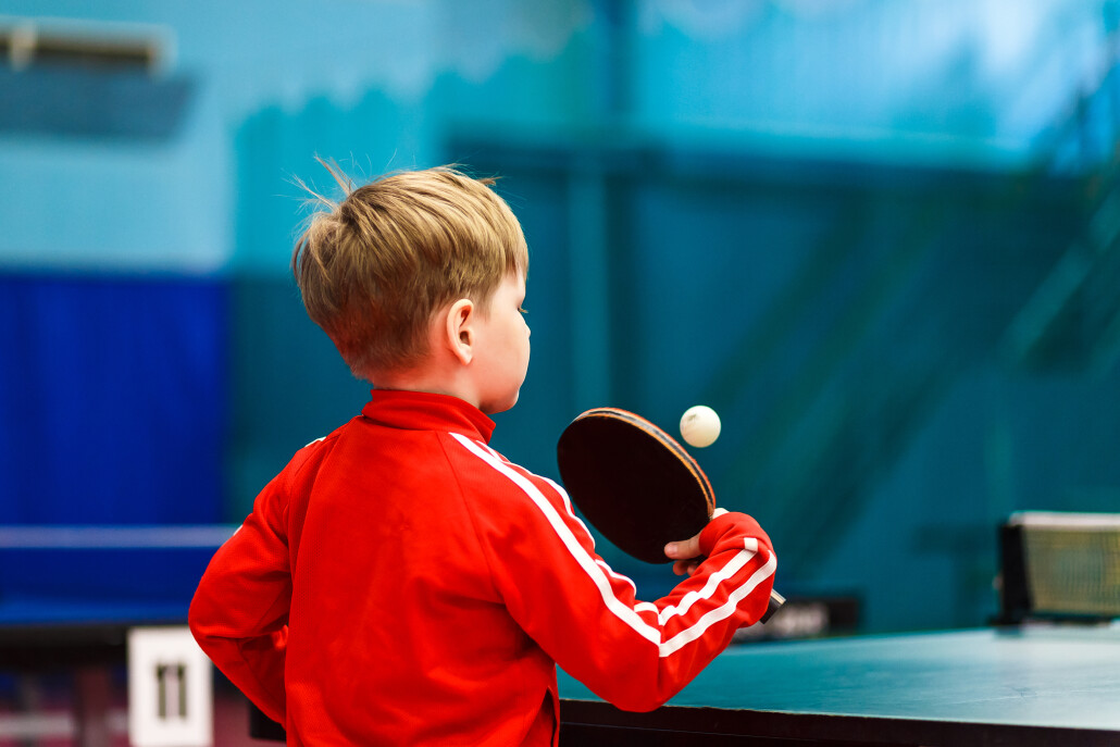a child plays table tennis in the gym