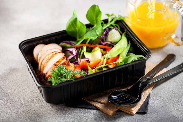 Healthy meal prep containers with chicken and vegetable salad.