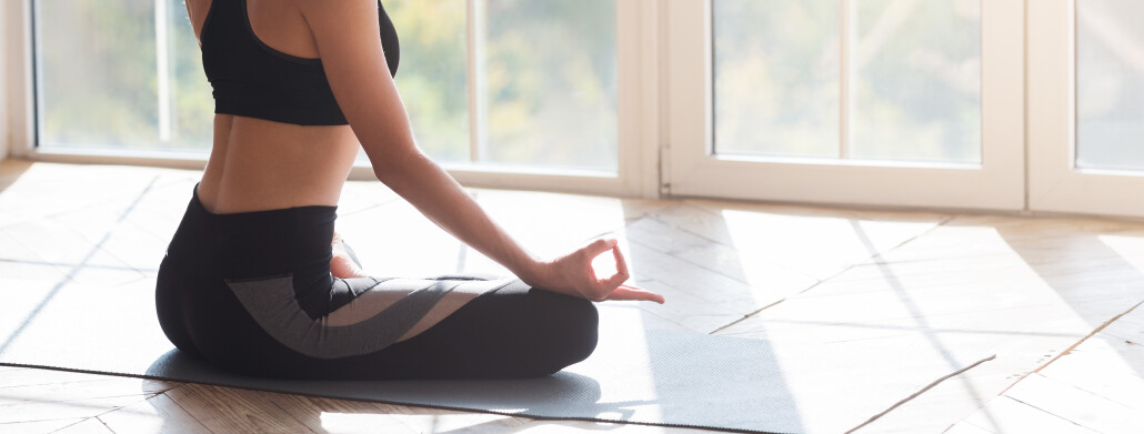 Cropped image of meditating woman sitting on yoga mat