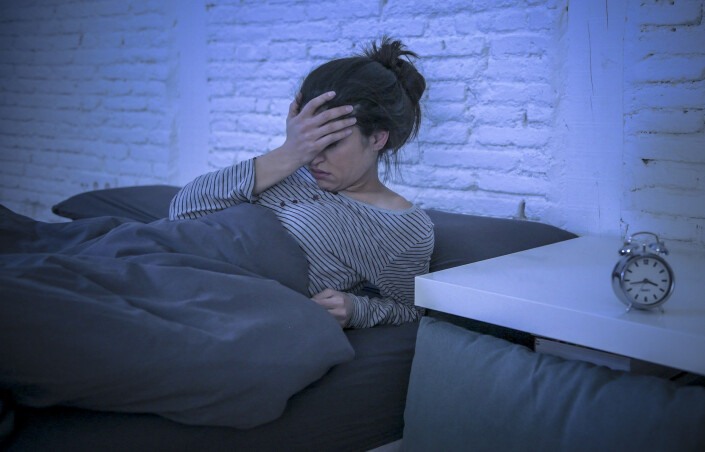 young beautiful sad and worried latin woman suffering insomnia and sleeping disorder problem unable to sleep late at night lying on bed awake